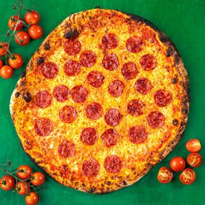Pepperoni pizza on a green background